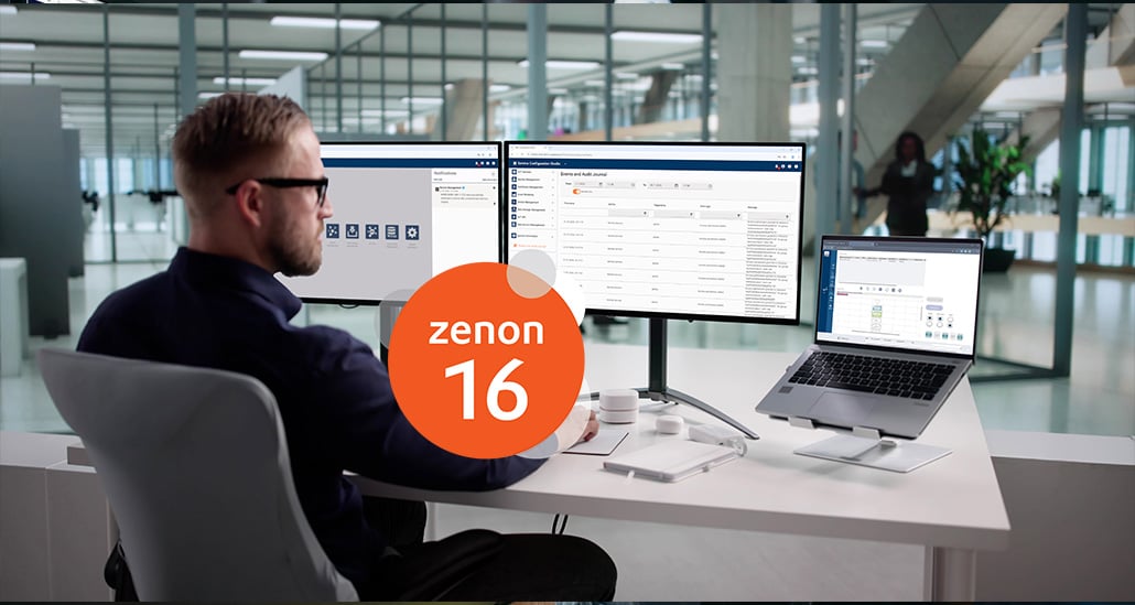 Mann mit Brille arbeitet an zwei Monitoren und Laptop in modernem Büro